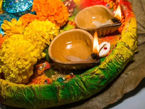 Clay diyas glowing among marigold flowers for Diwali
